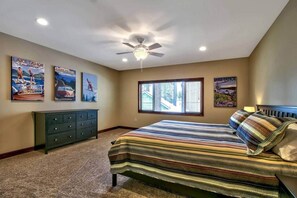 A bedroom with a bed, a ceiling fan, a dresser, and wall art depicting Lake Tahoe. - Ideally Located Condo - 6-min Walk to Casinos (South Lake Tahoe)
