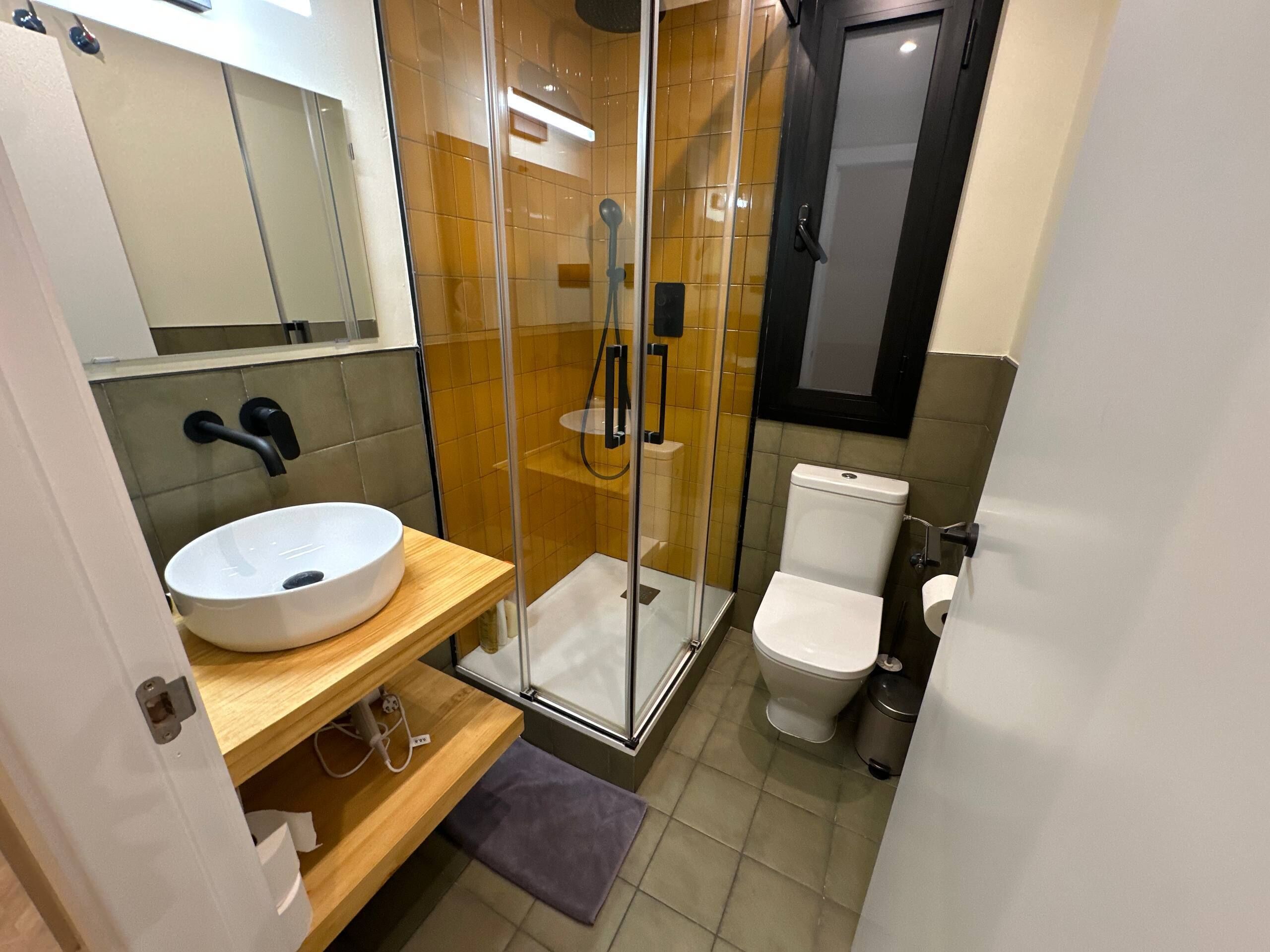 Une salle de bain moderne avec une douche à parois de verre, un lavabo blanc et des toilettes.