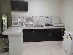 A kitchen with a microwave, sink, refrigerator, and cabinets.