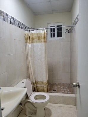 A small bathroom with a toilet, sink, and shower area. - Shop-Hospital-Fit6people (Changuinola)