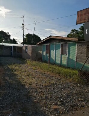 A fenced outdoor area with a building, power lines, and a clear sky. - Shop-Hospital-Fit6people (Changuinola)