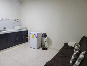 A compact kitchen with a refrigerator, a stove, and a fan. - Shop-Hospital-Fit6people (Changuinola)