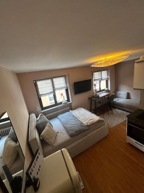 A compact room with a bed, a desk, a sofa, and a TV. - Little happiness city apartment (Würzburg)