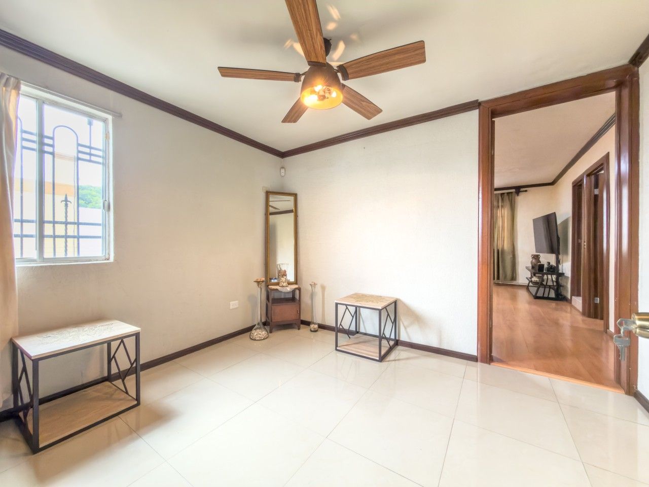 A spacious room with a ceiling fan, a large window, a mirror, and a small table.