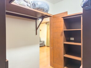 Una habitación con literas, una estantería de madera y una puerta que da a otra habitación.