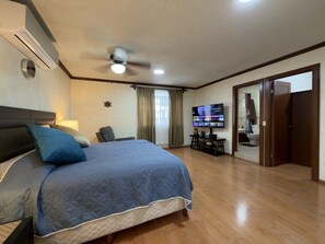 A hotel room with a bed, a ceiling fan, a TV, and a wooden floor. - Casa grande cerca del BBVA (Monterrey)
