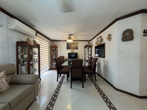 A living room with a sofa, a dining table with chairs, a TV, and decorative items on the walls. - Casa grande cerca del BBVA (Monterrey)