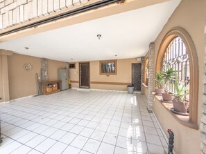 A spacious covered patio with a tiled floor, a small seating area, and potted plants. - Amplia Casa Familiar con Parking (Monterrey)