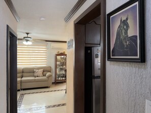 A hallway with a beige sofa, a wooden cabinet, and a refrigerator. - Casa grande cerca del BBVA (Monterrey)