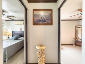 Un dormitorio con cama, una mesita de noche, un cuadro en la pared y una puerta que da a otra habitación.