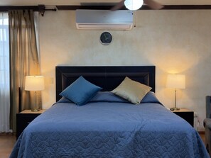 A hotel room with a bed, two bedside lamps, a clock, and an air conditioning unit. - Casa grande cerca del BBVA (Monterrey)