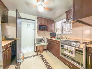 A kitchen with a stove, microwave, and oven, a water dispenser, and a television on a stand. - Amplia Casa Familiar con Parking (Monterrey)