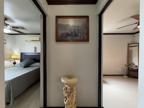 A bedroom with a bed, a bedside table, a wall-mounted painting, and a door leading to another room. - Casa grande cerca del BBVA (Monterrey)