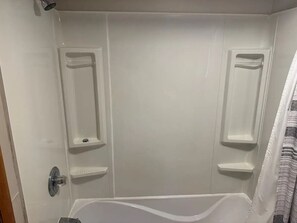 A bathroom with a bathtub, two vanity mirrors, and a shower curtain.