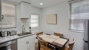 Cocina compacta con pileta, estufa y zona de comedor con sillas.