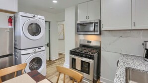 Una cocina compacta equipada con lavadora, microondas, horno y cafetera.