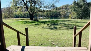 Une terrasse en bois offrant une vue sur une zone herbeuse et un plan d’eau.