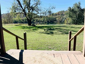 Une terrasse en bois offrant une vue sur une zone herbeuse et un plan d’eau.