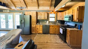 Une cuisine avec des meubles de rangement en bois, un réfrigérateur, une cuisinière et un four à micro-ondes.