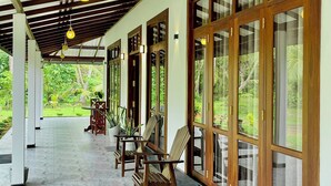 A covered corridor with wooden beams, large glass doors, and potted plants. - Peaceful private villa just steps from the beach in Habaraduwa (Habaraduwa)