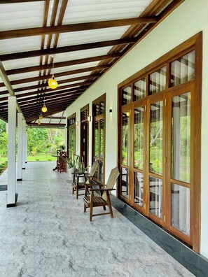A covered corridor with wooden beams, large glass doors, and potted plants. - Peaceful private villa just steps from the beach in Habaraduwa (Habaraduwa)