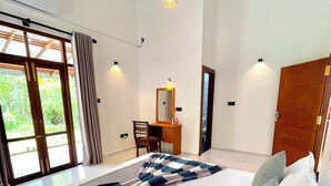 A bedroom with a large bed, a desk with a mirror, and a view through a glass door. - Peaceful private villa just steps from the beach in Habaraduwa (Habaraduwa)