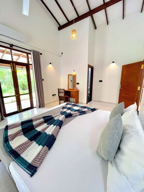 Een slaapkamer met een groot bed, een bureau met spiegel en uitzicht door een glazen deur.