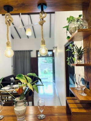 A dining area with wooden tables, hanging rope lights, and potted plants. - Peaceful private villa just steps from the beach in Habaraduwa (Habaraduwa)