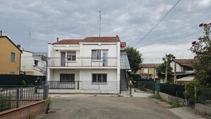 Ein zweistöckiges Wohnhaus mit Balkon, Auffahrt und umzäunter Garten.