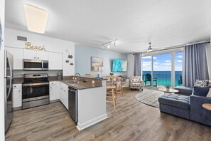 A modern kitchen with a dining area, a sofa, and a view of the ocean. - 3bd Beachfront Resort Condo| Pools, Hot Tubs & Views (Panama City Beach)