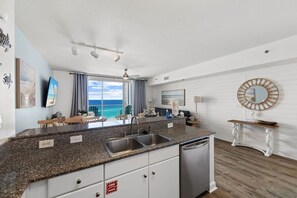 Eine moderne Küche mit Granit Arbeitsplatten, Edelstahlgeräten und Blick auf den Ozean.