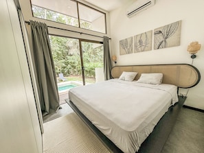 A bedroom with a bed, a window with curtains, an air conditioning unit, and a wall-mounted lamp. - Dreamers’ Refuge (adults only, private pool) (Provincia de Puntarenas)