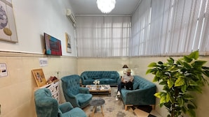 A room with teal armchairs, a sofa, a coffee table, and a potted plant.
