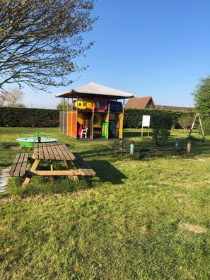 Ein Spielplatz mit Rutsche, Schaukeln und einem Picknicktisch.