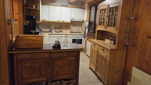 A kitchen with wooden cabinets, a stove, and a sink. - Fully-equipped family chalet with large garden 300m from lifts. (Leysin)