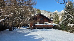 A wooden cabin with a balcony, surrounded by snow-covered trees and mountains. - Fully-equipped family chalet with large garden 300m from lifts. (Leysin)