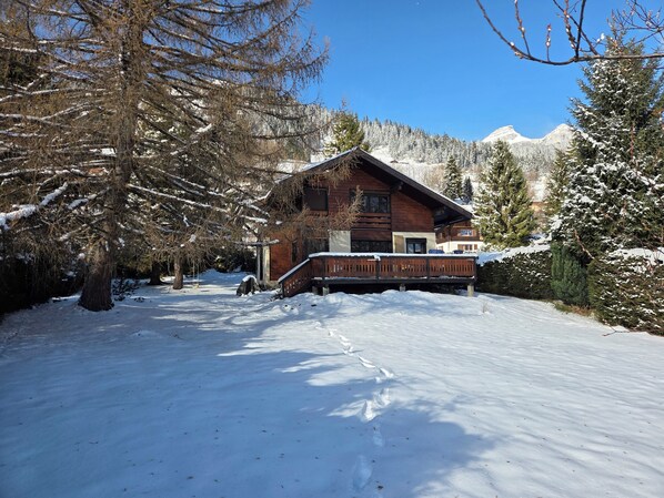 Une cabane en bois dotĂ©e dâun balcon, entourĂ©e dâarbres et de montagnes couverts de neige.