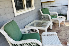A patio with wicker furniture, including chairs and a table.