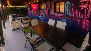 An outdoor seating area with a cityscape mural, a sofa, and a dining table. - Modern Retreat Near Beach, Las Olas & Hard Rock (Fort Lauderdale)