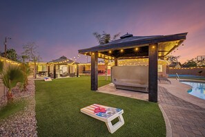 A backyard with a covered seating area, a barbecue grill, a pool, and a small American flag-themed table. - Scottsdalestays 11BR The Royal Palms Estate-Big Pool, Spa, Pickleball. (Phoenix)