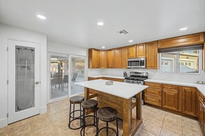 A kitchen with wooden cabinets, a white countertop, a central island with stools, a microwave, and a stove. - 50% OFF Scottsdalestays 11BR The Royal Palms Estate-Big Pool, Spa, Pickleball. (Phoenix)