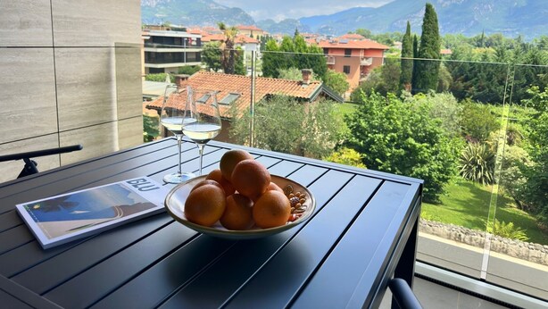 A balcony with a table, a bowl of oranges, and a magazine.