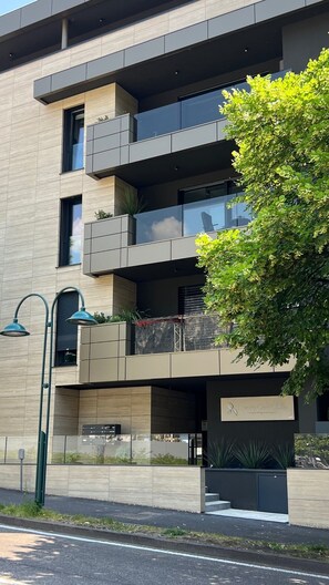 Ein modernes, mehrstöckiges Gebäude mit Balkonen, einer Straßenlaterne und einem Schild mit der Aufschrift 'Luxury Garden Life'.