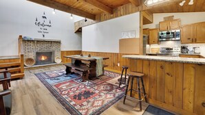 A rustic kitchen with wooden cabinets, a brick fireplace, and a bar area.
