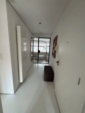 A modern hallway with a sliding door leading to a balcony, a bench, and a wall-mounted light fixture. - Superb new apartment center ostend (Oostende)