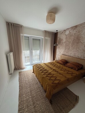 A bedroom with a bed, curtains, a radiator, a ceiling light, and a view through a window with blinds. - Superb new apartment center ostend (Oostende)