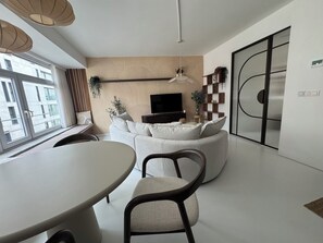 A modern living room with a sofa, a TV, a dining table, and a large window. - Superb new apartment center ostend (Oostende)