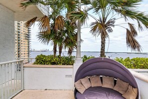Een balkon met een hangstoel, palmbomen en uitzicht op zee.
