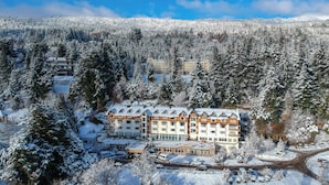Un hotel a più piani con un paesaggio innevato, circondato da una fitta foresta.