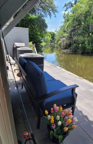 Une terrasse avec un canapé bleu, des climatiseurs et un tulipe en pot.